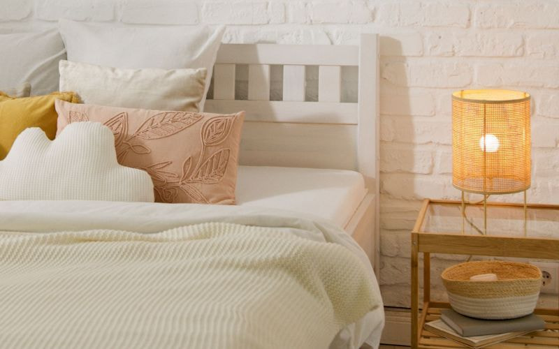 Giường tông sáng với đầu giường gỗ, bàn đầu giường và đèn ngủ