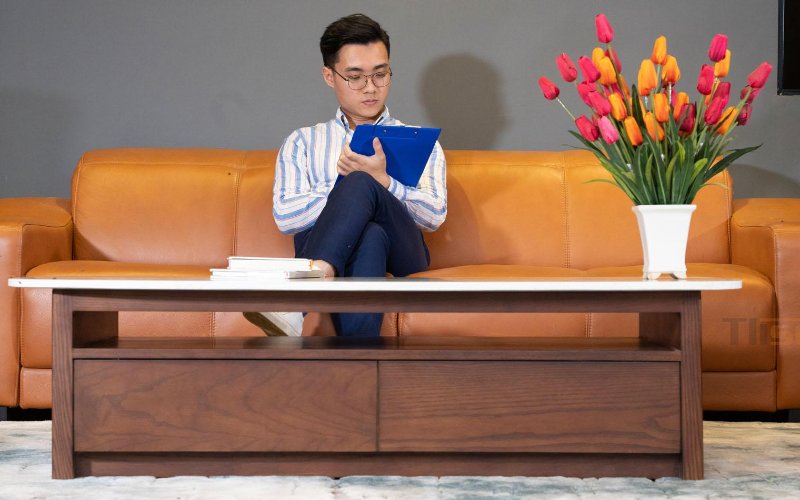 Trực tiếp xem mẫu và ngồi thử giúp đánh giá sofa trước khi chọn mua. Người ngồi trên sofa bọc da màu nâu tại khu trưng bày